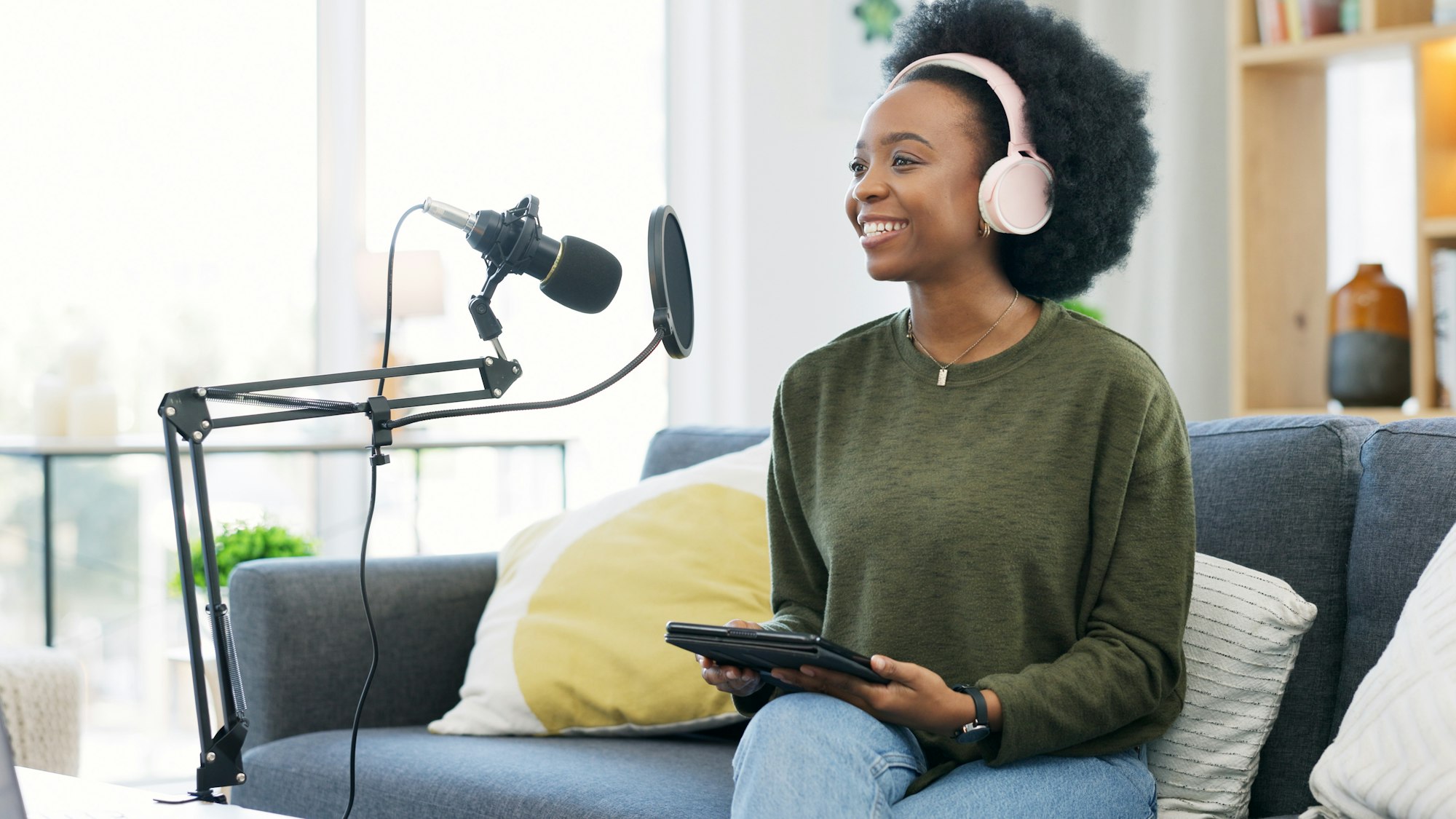 Cool journalist using digital tablet, talking into microphone and hosting podcast or broadcasting n